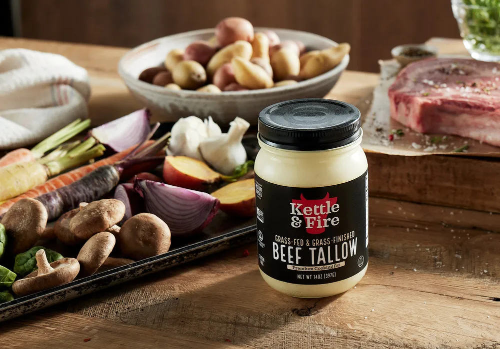 A jar of Kettle & Fire beef tallow next to vegetables and steak